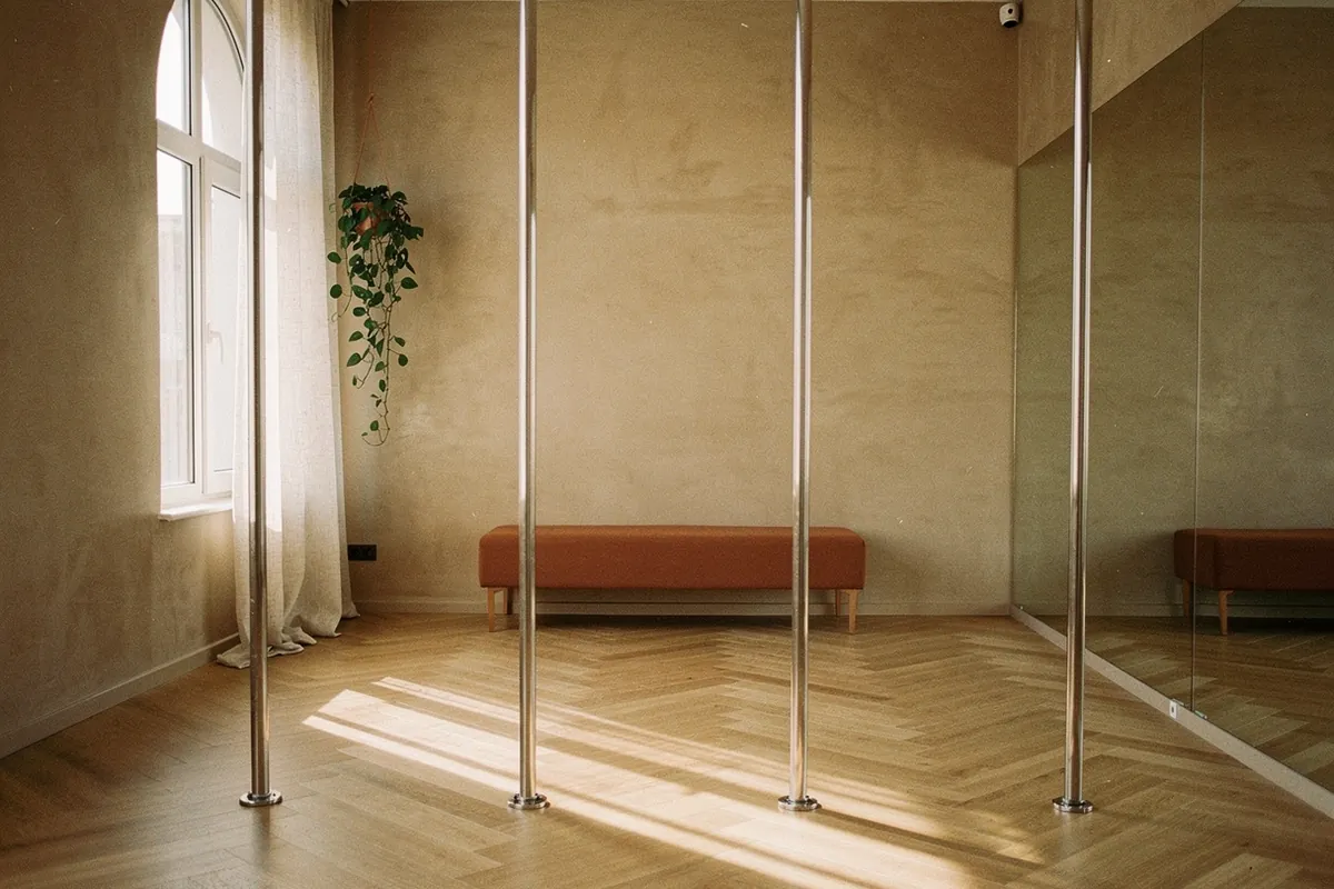 Sala do estúdio de pole dance com barras em fila, espelho e piso de madeira