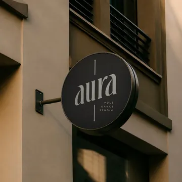 Placa redonda com a marca Aura na fachada do estúdio